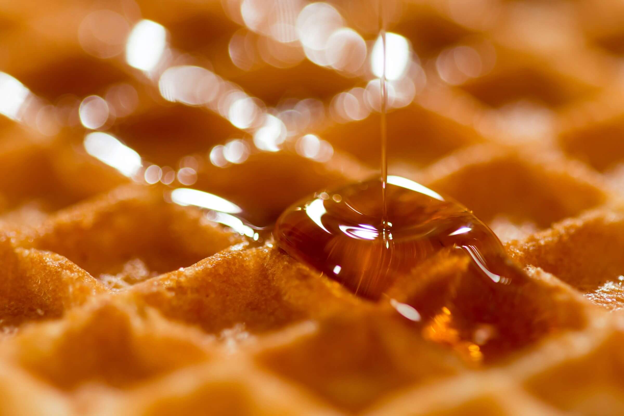 syrup being poured on a waffle