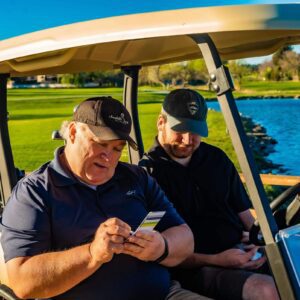 two men writing on golf score card in a golf cart