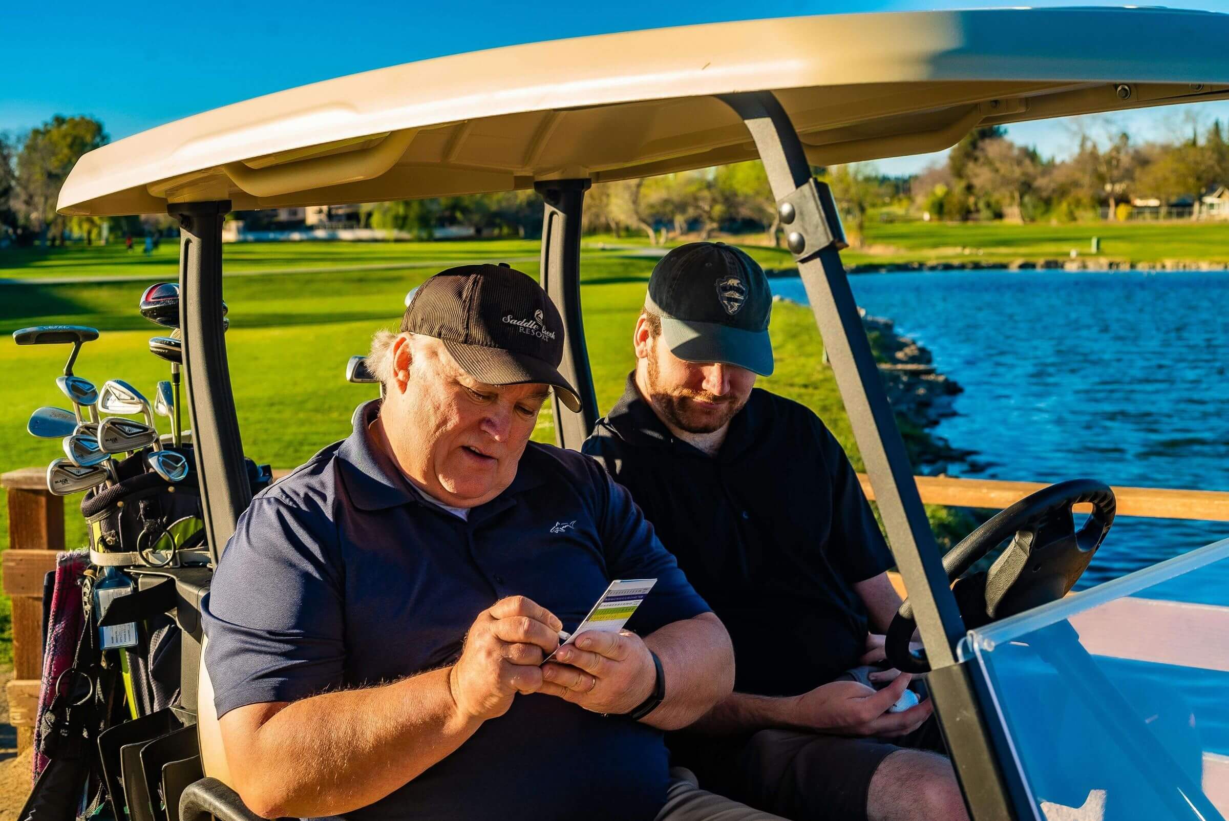 two men writing on golf score card in a golf cart